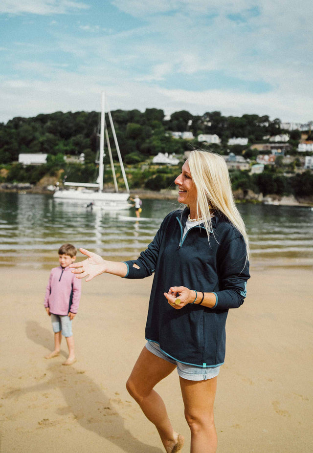 Woman Enjoying Beach in Navy Bamboo Sweatshirt: A woman stands on a sandy beach, wearing a navy bamboo sweatshirt. The soft and sustainable fabric provides comfort while she enjoys the seaside breeze. Embrace casual elegance and eco-conscious fashion with this navy bamboo sweatshirt.