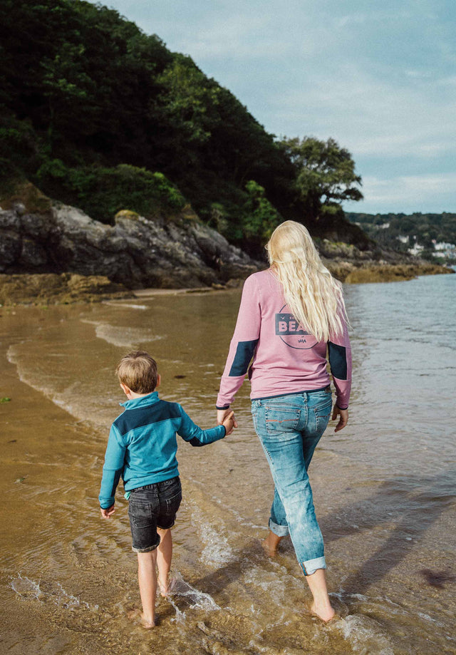 Woman walking on beach holding hands with boy both wearing Jellymud bamboo jumpers