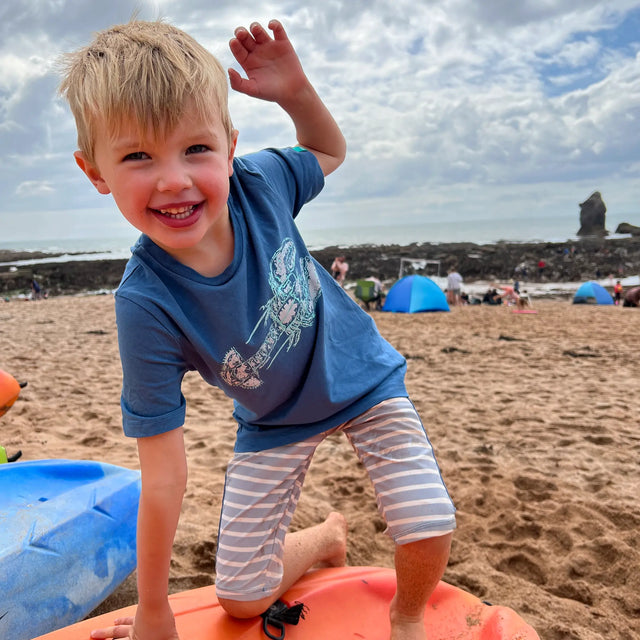 Boy on the beach wearing a Jellymud bamboo t-shirt featuring a limited edition John Aspden print