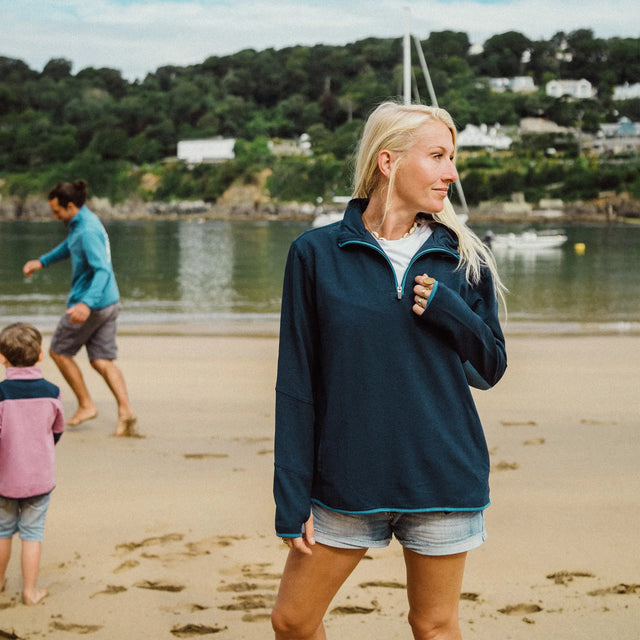 Woman on beach wearing a Jellymud Women's Peak Quarter-Zip Sweatshirt in navy.