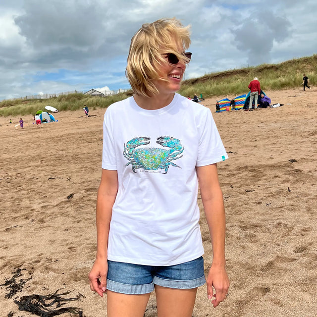 Woman on the beach wearing a Jellymud white bamboo t-shirt featuring a limited edition John Aspden crab print