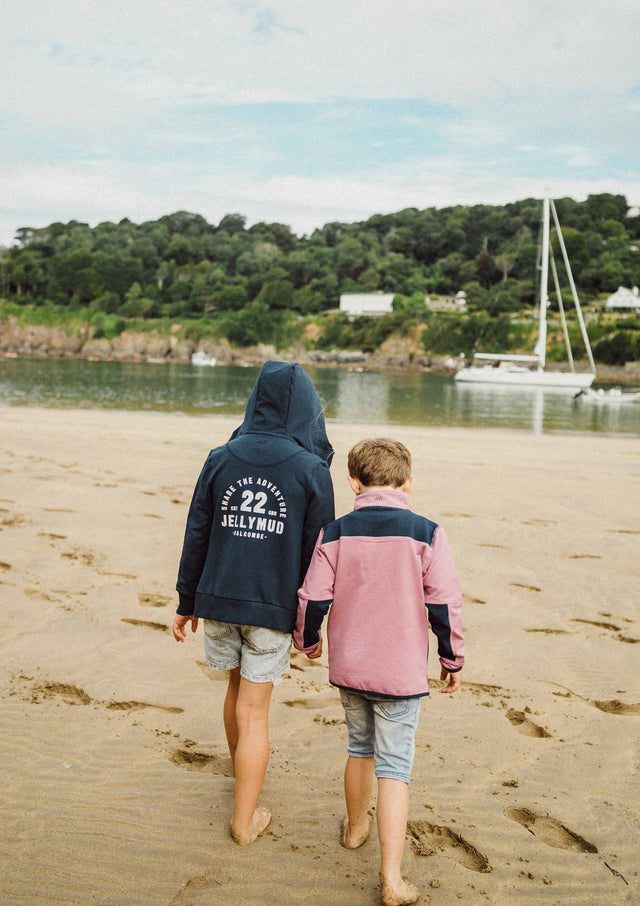 Back view of Jellymud Junior Burton Bamboo Hoodie in Navy. Children on the beach.