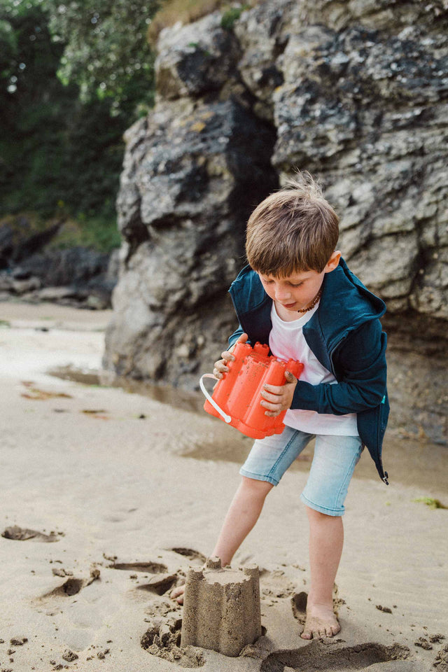 Boy on the beach making a sandcastle whilst wearing a Jellymud Bamboo T-Shirt and Hoodie.